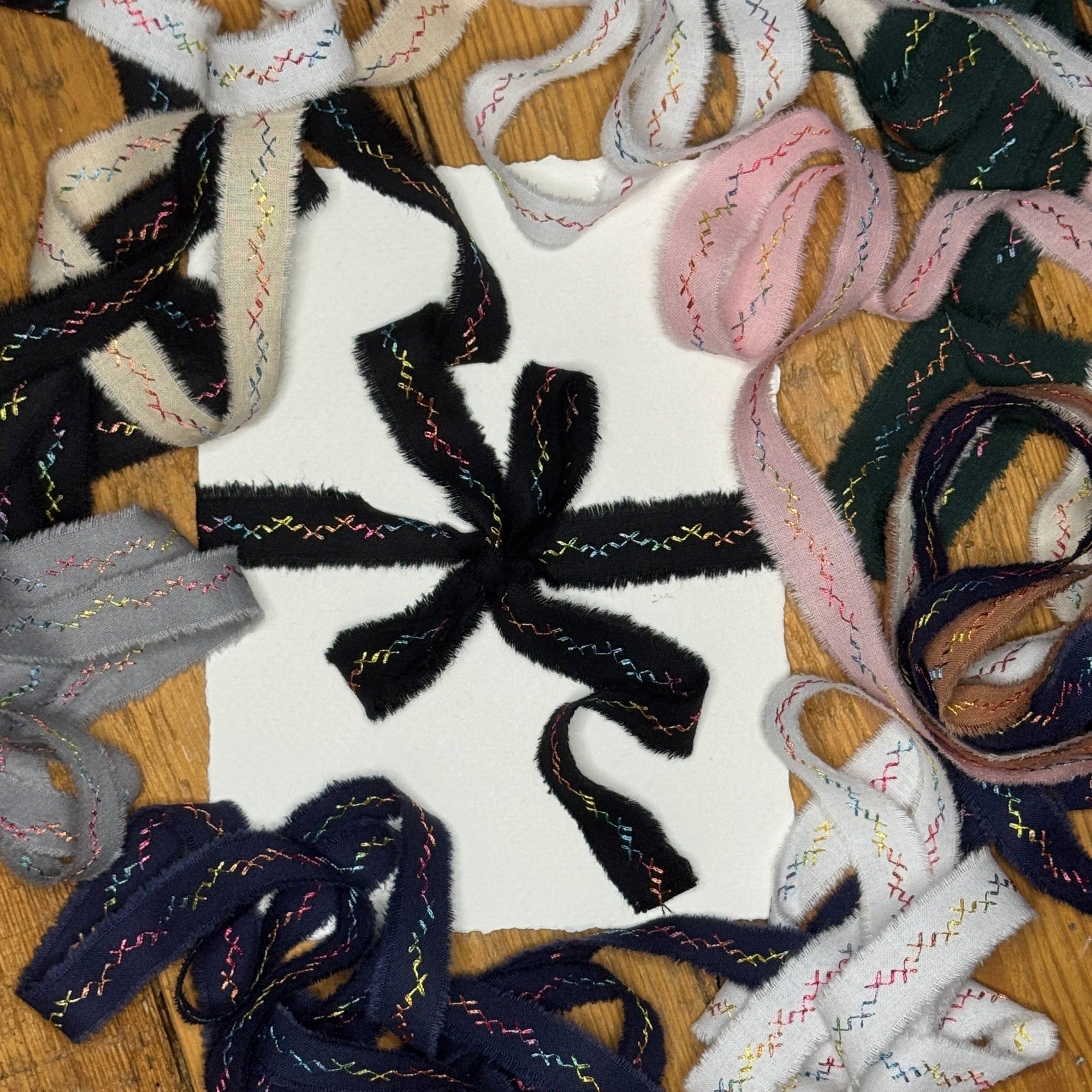 Collection of colorfull embroidered hand-torn frayed edge ribbons shoelaces on a wooden rustic surface