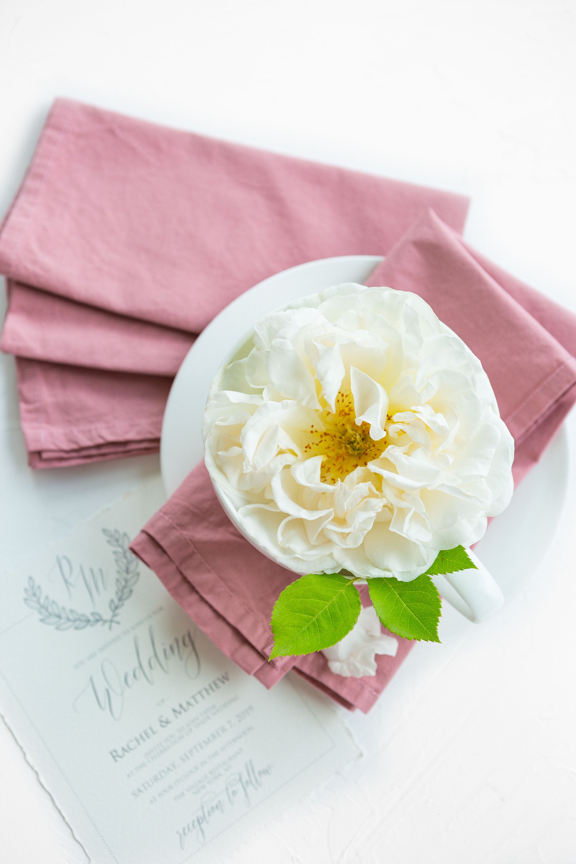 Dusty rose napkins set for wedding table with white rose