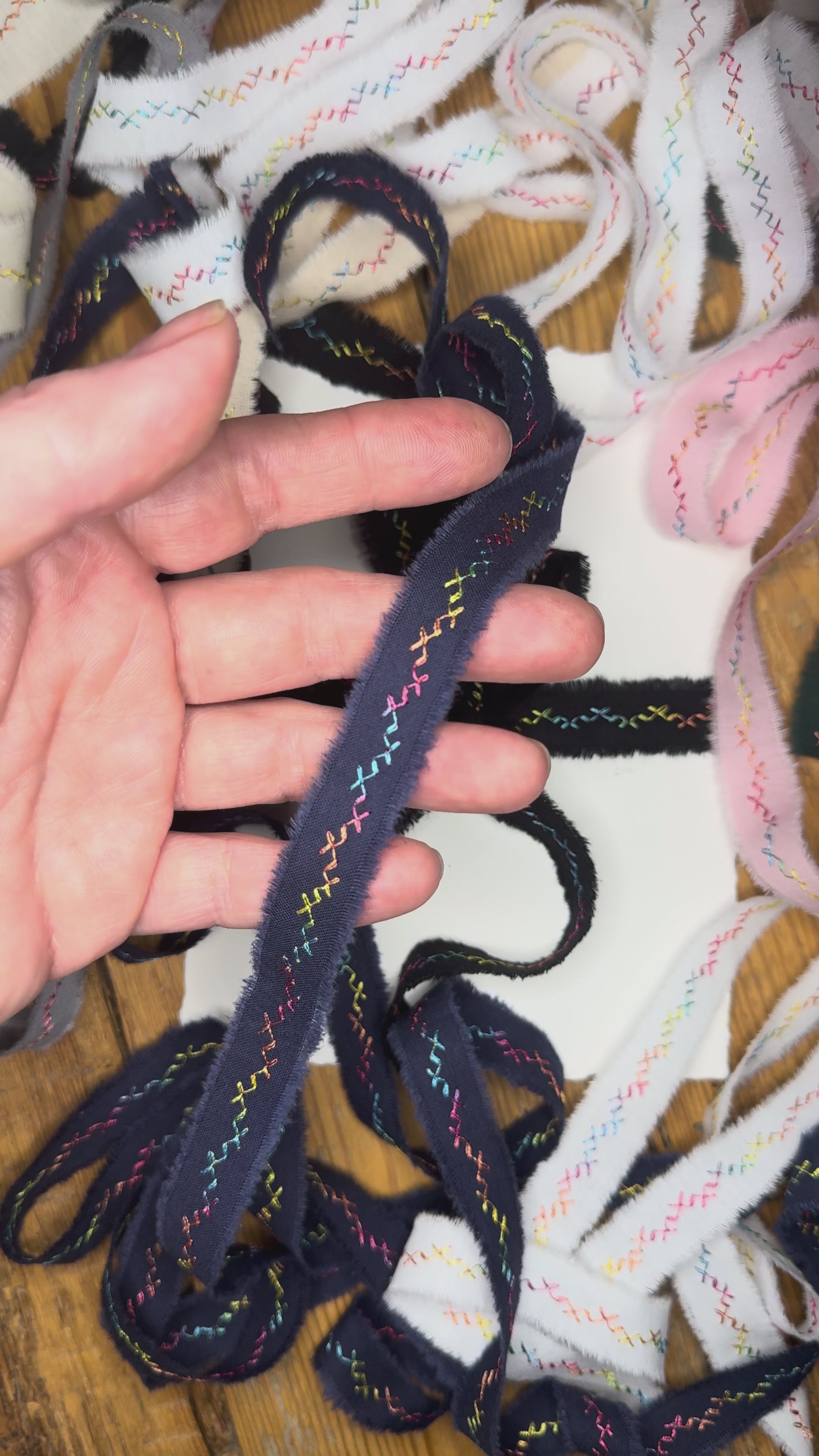 Embroidered hand-torn cotton ribbon on rustic wooden table